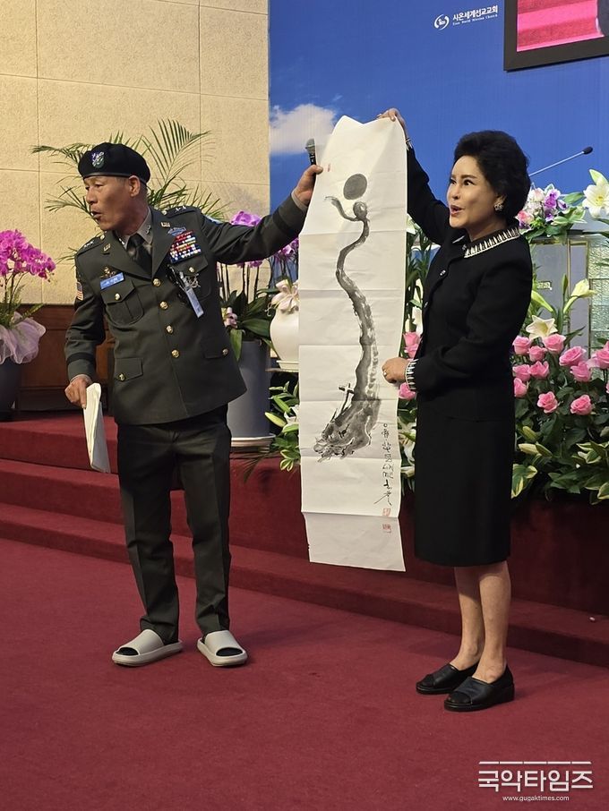 예술문화 사령관 김경호 화백은 신현옥 목사에게 축하로 그림을 선물하고 있다
